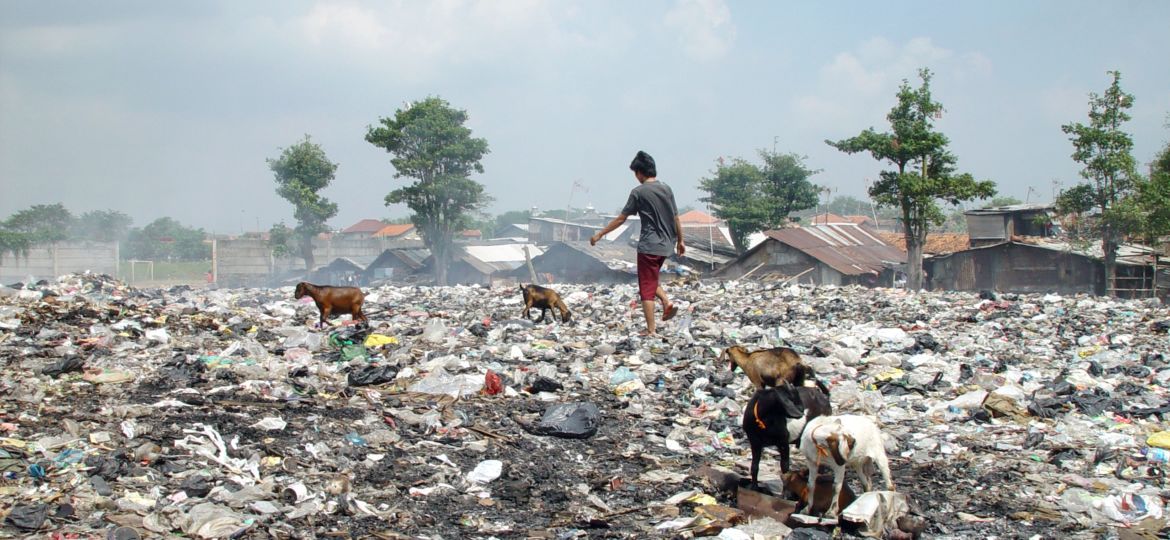 waste pickers walk on top of a mountain of trash in jakarta